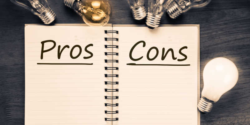「Pros」と「Cons」が書かれているノートと電球の画像