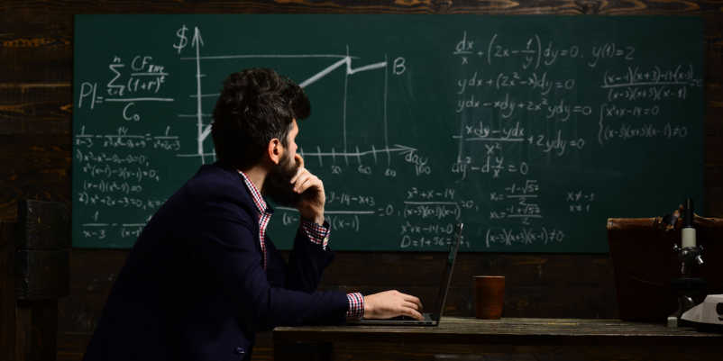 黒板に書かれた数式を眺める男性